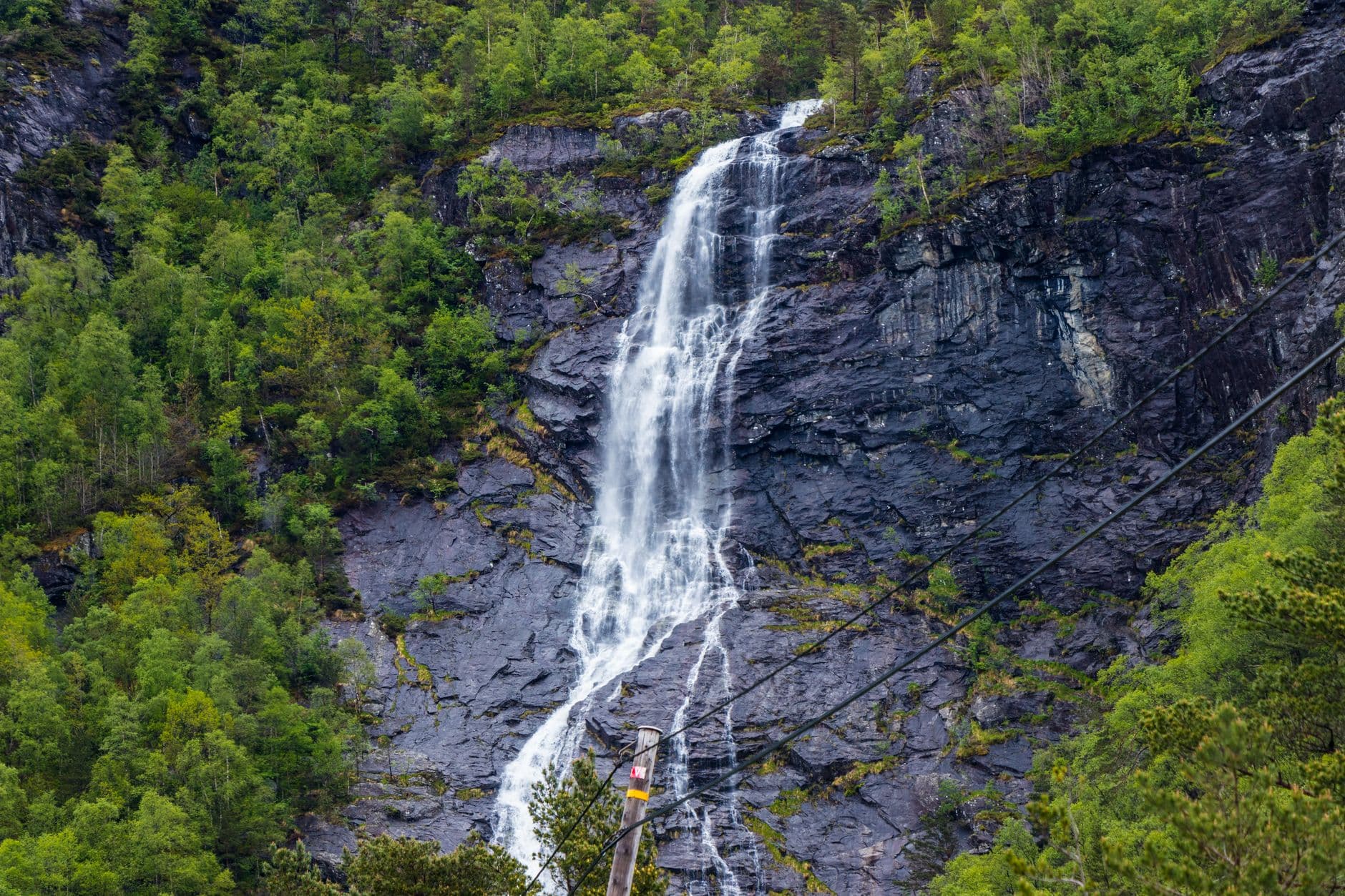 A beautiful waterfall in the Kazbegi mountains surrounded by green vegetation on a sunny day